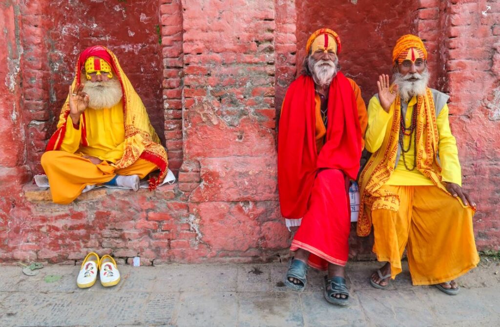 three hindu sadhus wearing saffron robes giving blessings